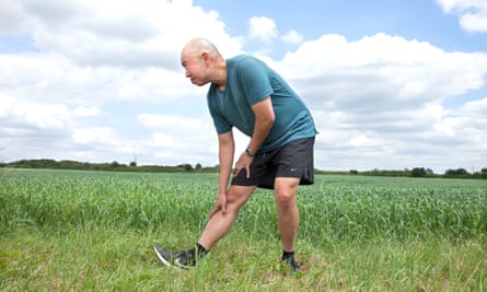 A man in a field doing a leg stretch