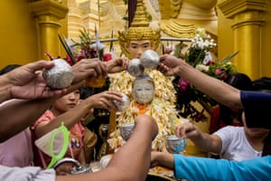 Devotees pour water on a Buddha statue