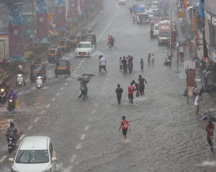 People wade through flood water in a street in Mumbai