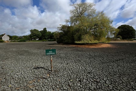 A dried-up pond with a ‘No Fishing’ sign sticking out of the mud