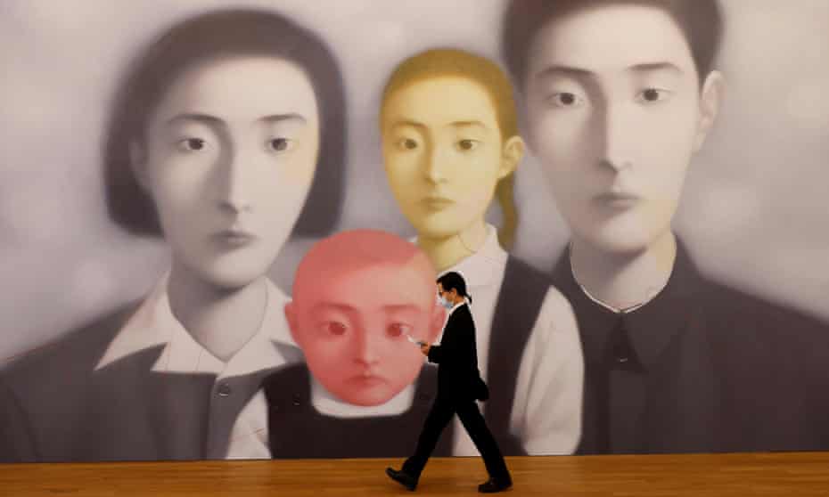 A security guard walks in front of Bloodline – Big Family No 17 by Zhang Xiaogang at M+