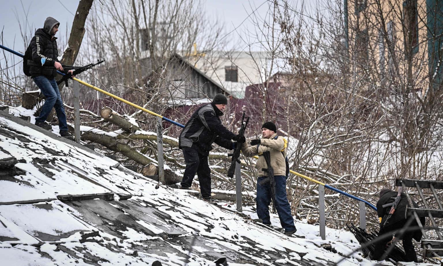 Members of an Ukrainian civil defence unit pass assault rifles to the opposite side of a blown-up bridge on Kyiv’s northern front, 1 March.