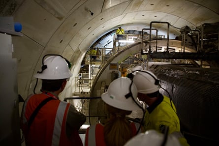 Workers in hard hats observe a tunnel boring machine ring building