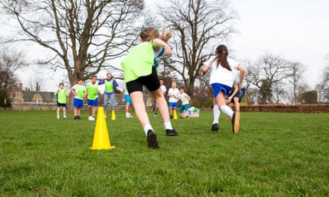 Children run around cones during a physical education session.