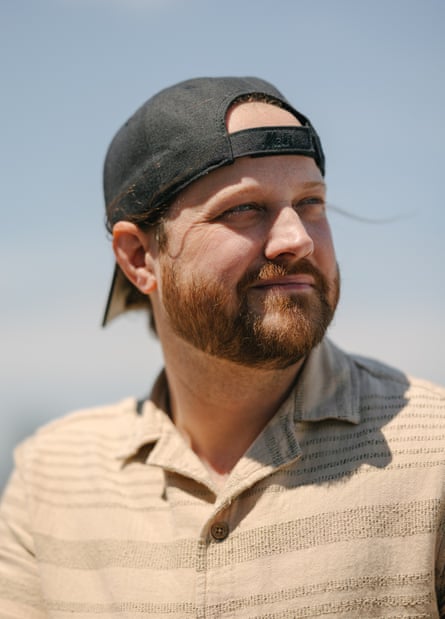 portrait of a man in a baseball cap looking outward with the sky and clouds as background