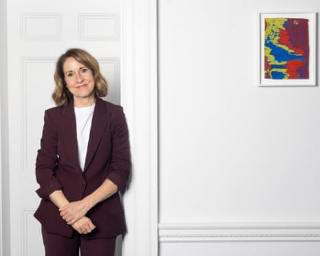 Liz Kendall in a burgundy suit stands with hands clasped in front of a white door
