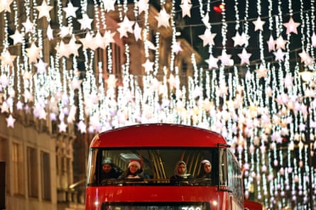 People on a London double-decker bus look out at Christmas lights