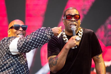 Busta grimaces while holding the mic as Spliff gesticulates towards him