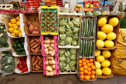 View of stacked boxes of colourful fruit and veg including peppers, broccoli, cucumbers, melons, oranges, cauliflowers and butternut squashes.