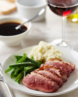 Duck breast served with mashed potato and green beans. Glass of red wine and sauce on background.