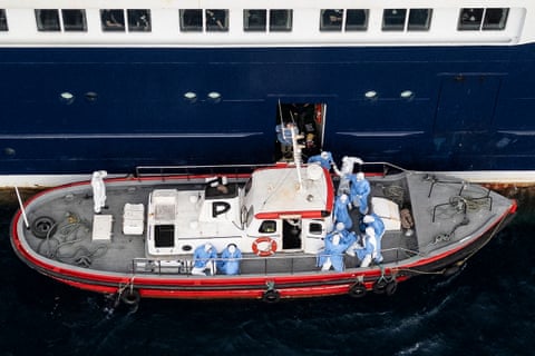 A small boat docked alongside the Hondius with medics in protective gear on the deck qhiukiqrihtinv