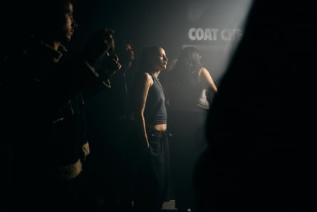Young people stand in a club next to a sign that says ‘coat check’