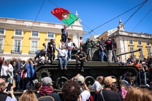 People climb old military vehicles in Lisbon