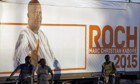 People stand in front of a campaign poster for Burkina Faso presidential candidate Roch Marc Kabore in Ouagadougou.