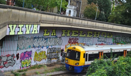 Graffiti by the side of a railway line as a train passes.
