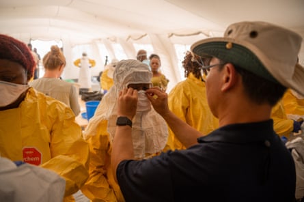 People in full PPE or being helped into PPE.