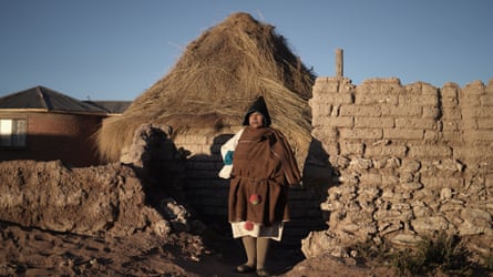 A woman standing in front of a small building.