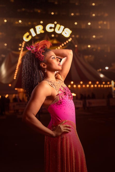 a woman in a pink dress stands near a banner that reads ‘circus’