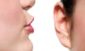 Closeup of a woman whispering into another woman's ear
