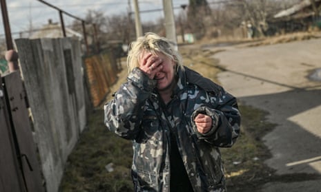 A woman reacts to the sound of shelling while outside her house in Chasiv Yar village, near Bakhmut