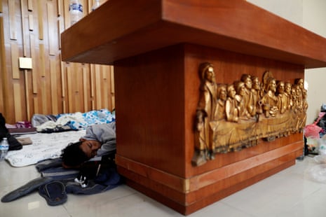 A Central American migrant, moving in a caravan through Mexico, sleeps behind an altar inside a Catholic church which also serves as a temporary shelter, in Tlaquepaque, Jalisco state 18 April