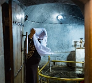 A woman covers her head with a white headscarf which has been bathed in the sacred spring.