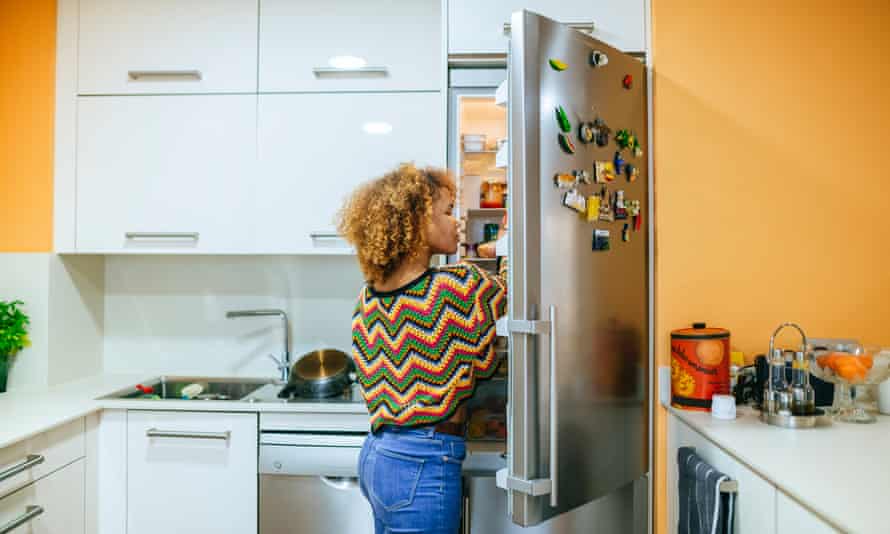 Woman opens the fridge in her kitchen