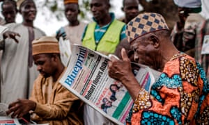 A man reads a national newspaper announcing the victory of Muhammadu Buhari