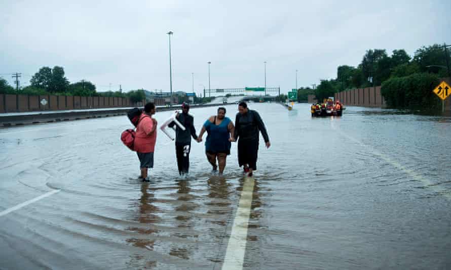 People make their way onto an I-610 overpass after being rescued from flooded homes during the aftermath of Hurricane Harvey on 27 August 2017 in Houston, Texas.