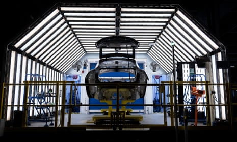 The bodyshell of an Aston Martin DBX at the company’s factory: it is seen in near-silhouette from the rear with the bootlid up.