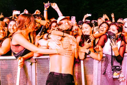 Fan hugs shirtless man over wall of crowd