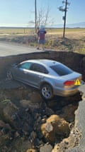 The sinkhole claims a sedan.