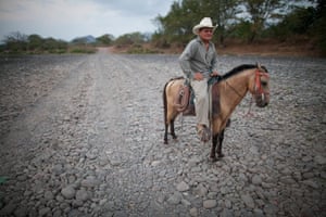 Oscar Alexis Maldonado Ramírez rides his horse Palomo along a dry stretch of the Río Nacaome