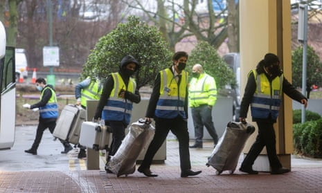 Workers carry passengers’ luggage to a Holiday Inn hotel near Heathrow airport on Tuesday after new quarantine measures were brought in.