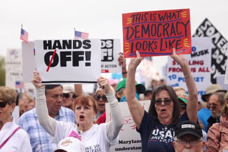 Demonstrators holding up 'Hands Off' and pro-democracy placards