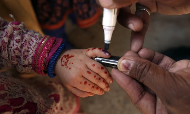 A health worker marks a child’s finger with a pen to show the polio vaccine has been given