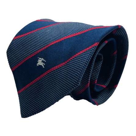 A rolled up Burberry tie with insignia. Th tie is wide blue and red pinstripe.