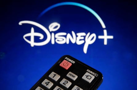 A remote control in front of a television screen showing a Disney + logo