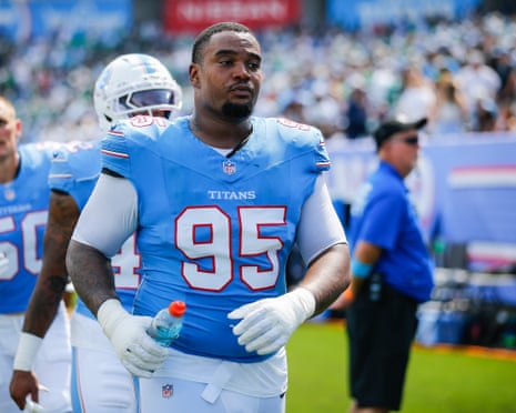 Titans defensive lineman Jordan Elliott walks across the field holding a water bottle