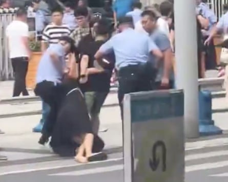 A screenshot shows at least two people being forcibly pulled aside by a group of uniformed and plain clothes police at a demonstration outside the city hall in Jiangyou.