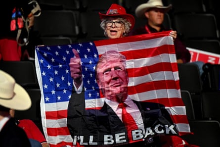 woman wearing red cowboy hat holds US flag with white man’s photo