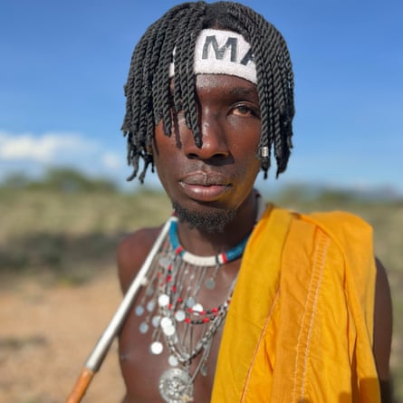 Samburu singer Jalven Brave, with a headband, his hair in braids and an orange garment over his shoulder