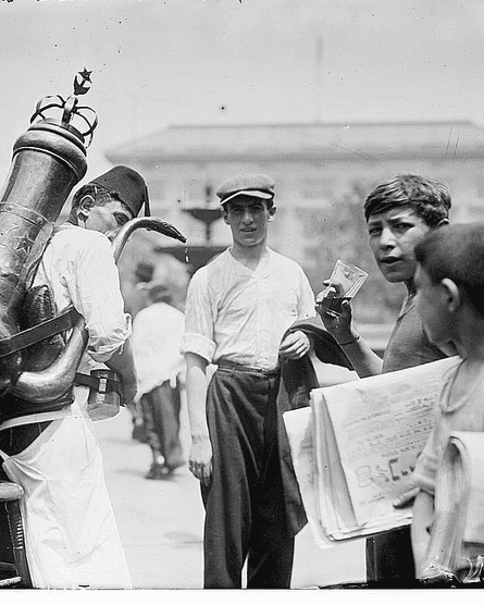 Boys sell cool drinks in the street in a black-and-white photo