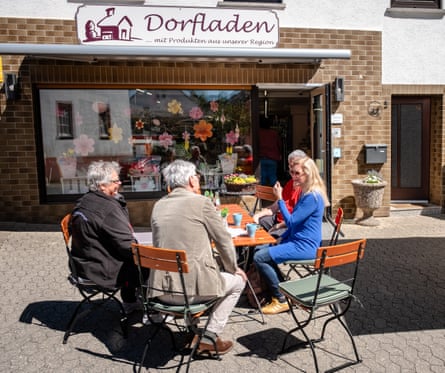People sitting round a table outside the shop having a chat and a coffee.
