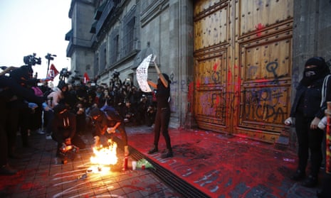 A masked female protester stands with a sign at the entrance to the national palace in Mexico City on 14 February. 