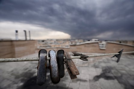 Close-up of clothes clips covered in soot from burnt fuel as smoke rises in the distance.