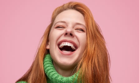 Laughing woman with long red hair on pink background.