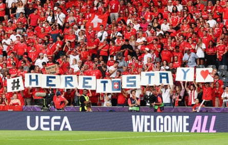 Switzerland fans at Euro 2025 hold up a tifo which reads: ‘Here To Stay’