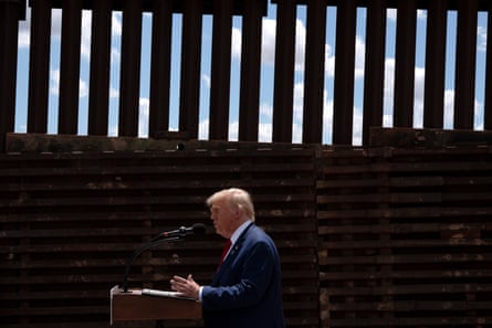 man speaks behind podium and microphone in front of wall