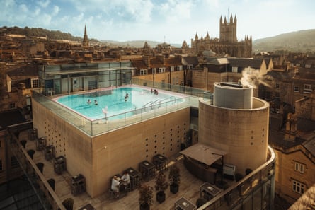 A smart rooftop pool on top of a building made of bath stone, with a view of the city around it
